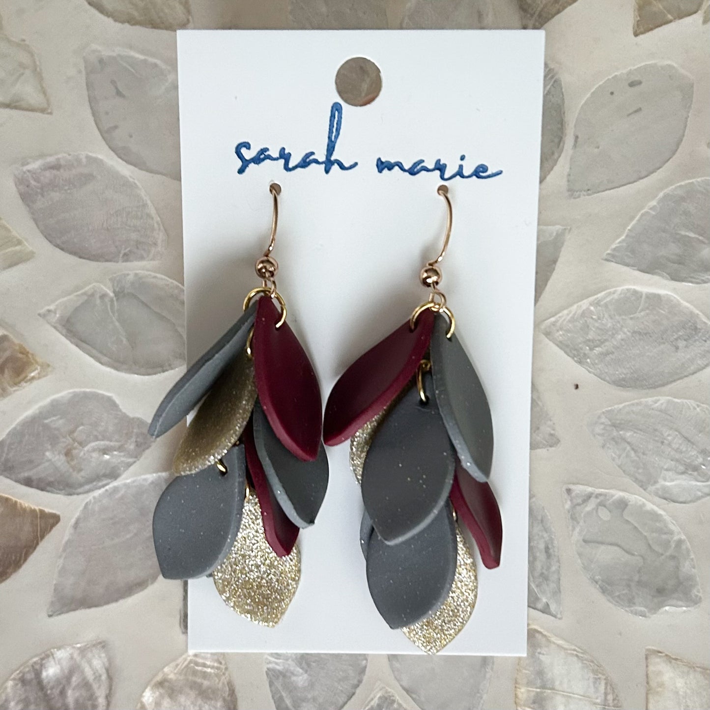 Gray, gold and maroon teardrop shapes dangle from hook earrings