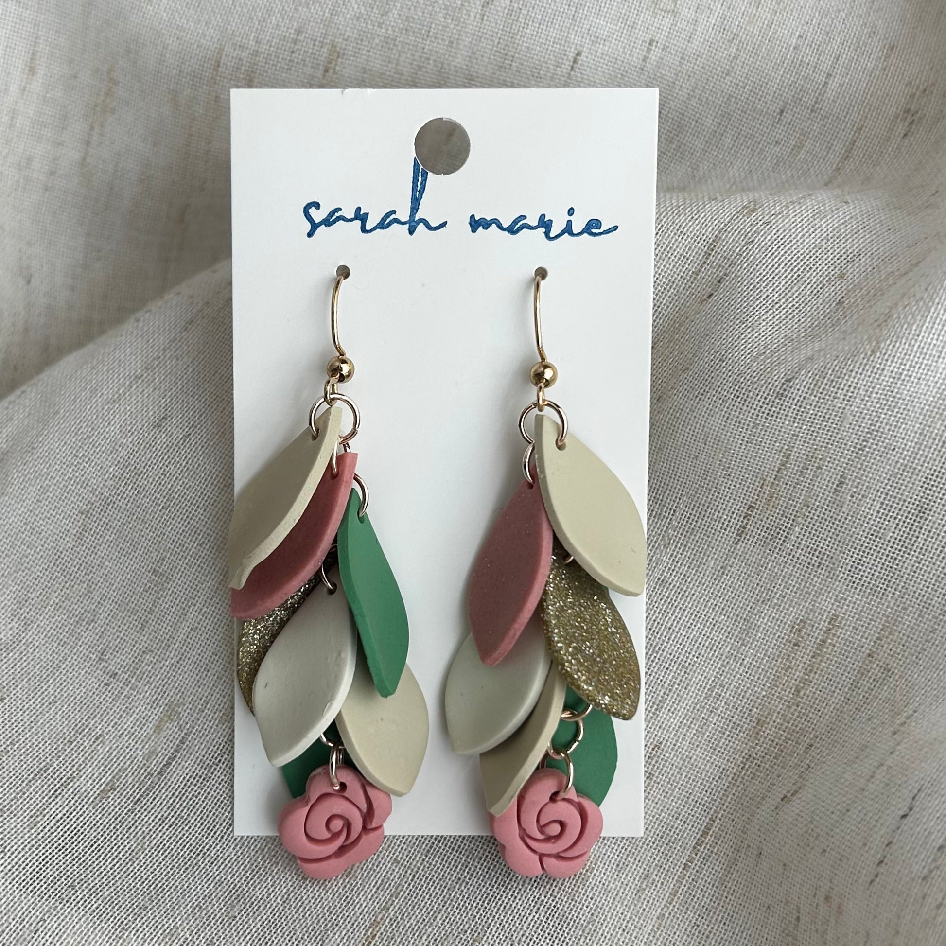 Pink, green and ivory earrings on a 'Sarah Marie' branded card against a textured fabric background