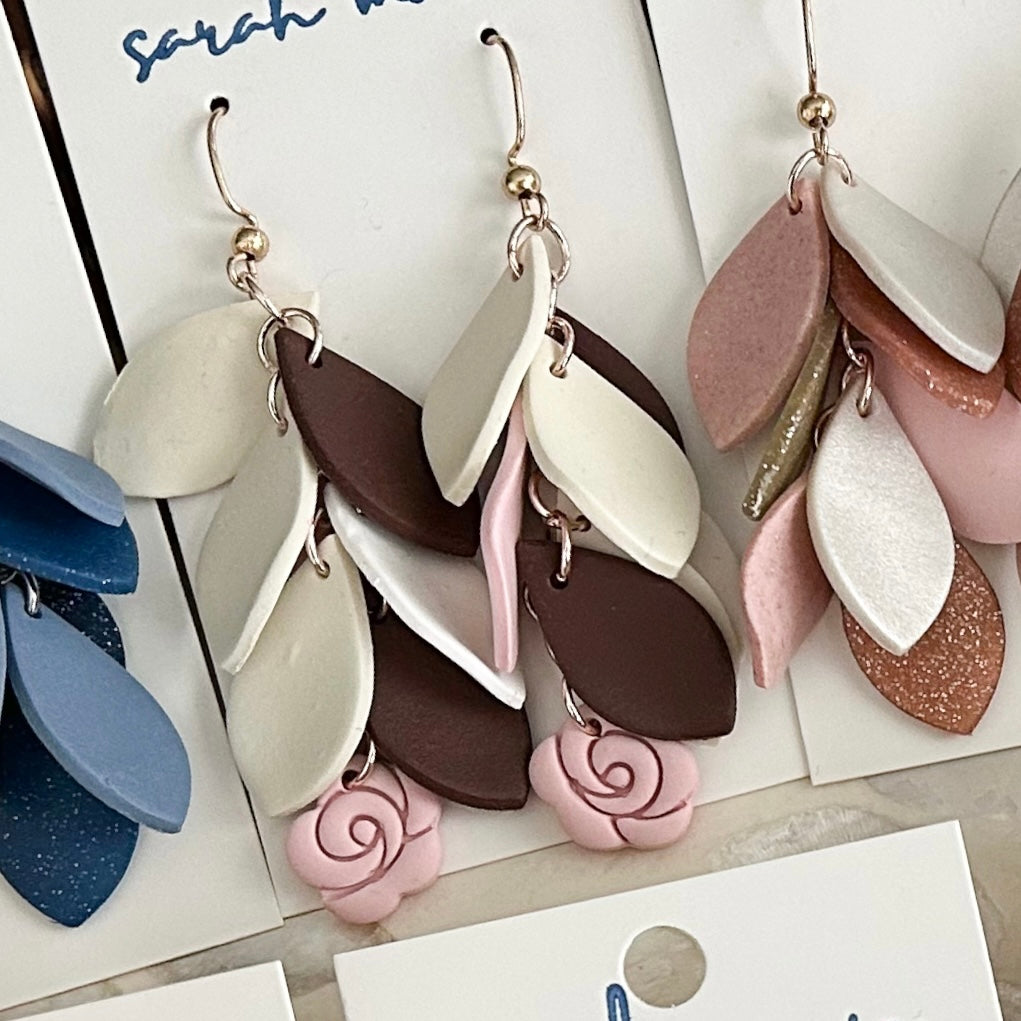 Pink ivory and brown leaf-shaped earrings on a white surface with 'sarah' branding.